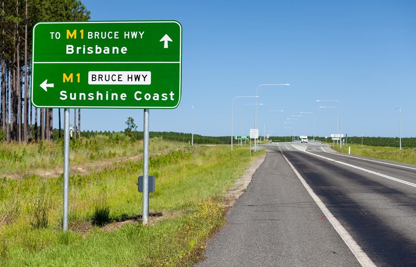 Bruce Highway road sign positioned next to empty motorway in Queensland Australia