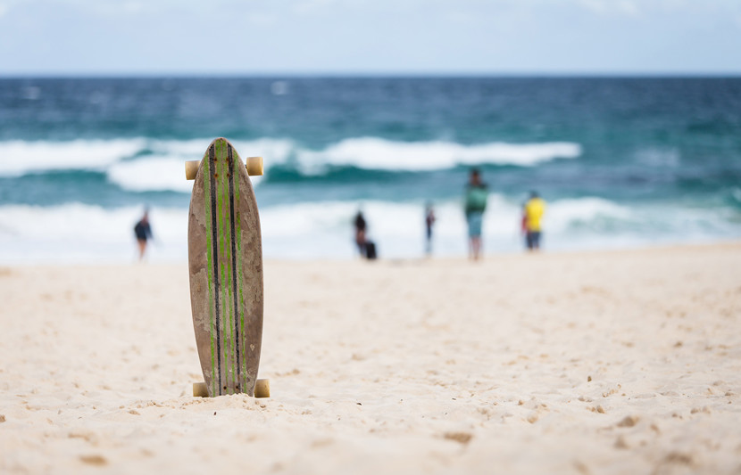 skateboard planted in the sand with the ocean backdrop
