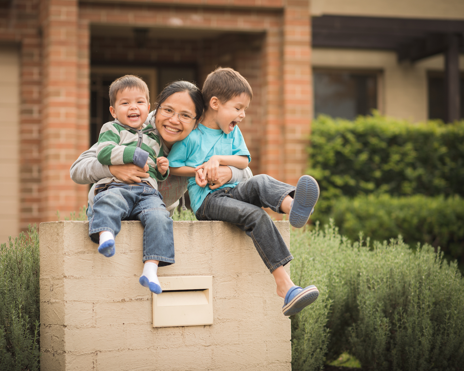 Mother with her 2 young children outside home from new social and affordable housing