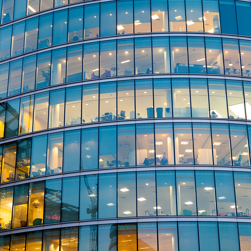 Lights and reflections in the windows of a city office building in the evening