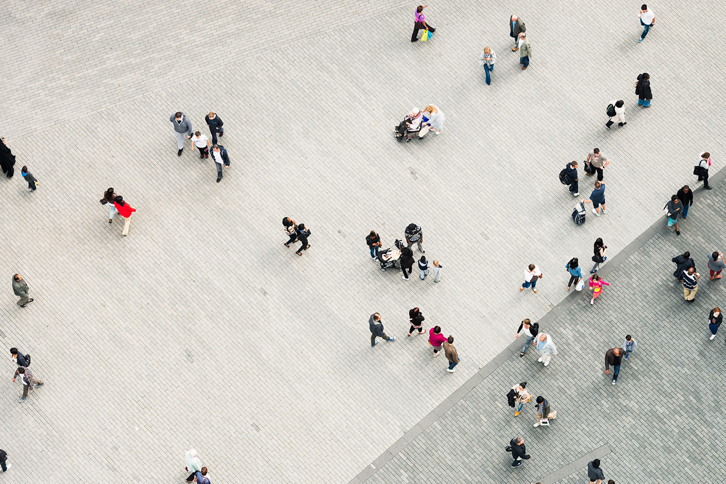 aerial view of paved urban square with pedestrians walking in the city