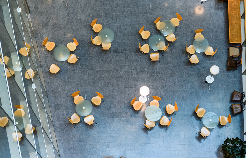 Overhead view of modern office building open plan meeting area with tables and chairs.