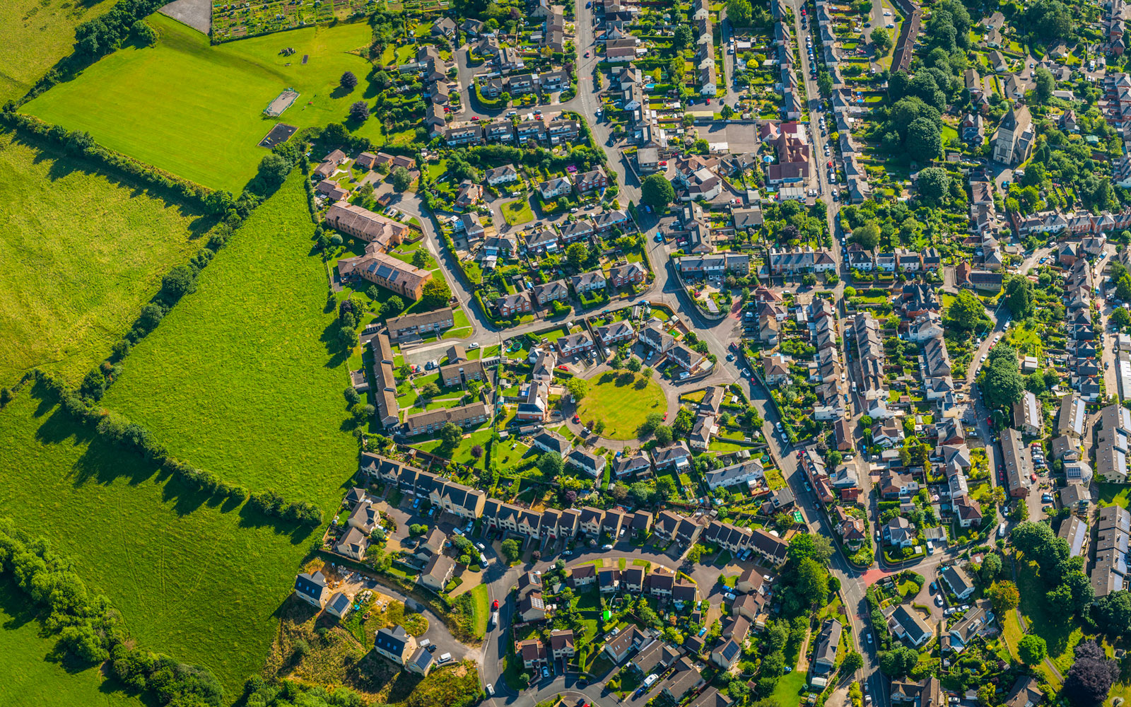 Birdseye view of suburban residential community with houses, streets, trees and park spaces