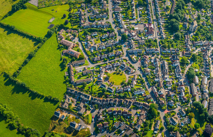 Birdseye view of suburban residential community with houses, streets, trees and park spaces