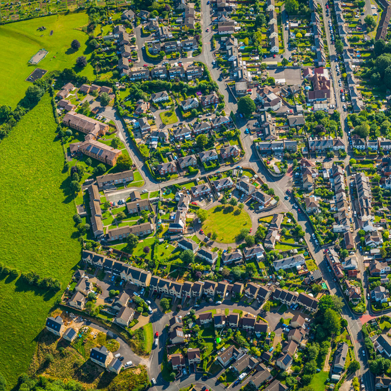 Birdseye view of suburban residential community with houses, streets, trees and park spaces