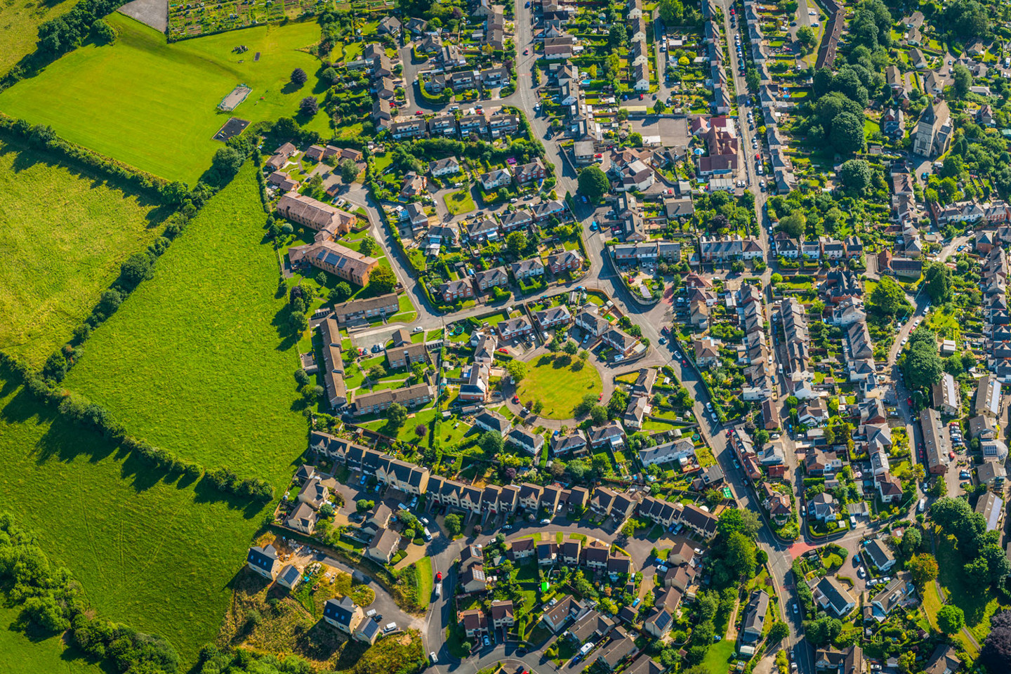 Birdseye view of suburban residential community with houses, streets, trees and park spaces