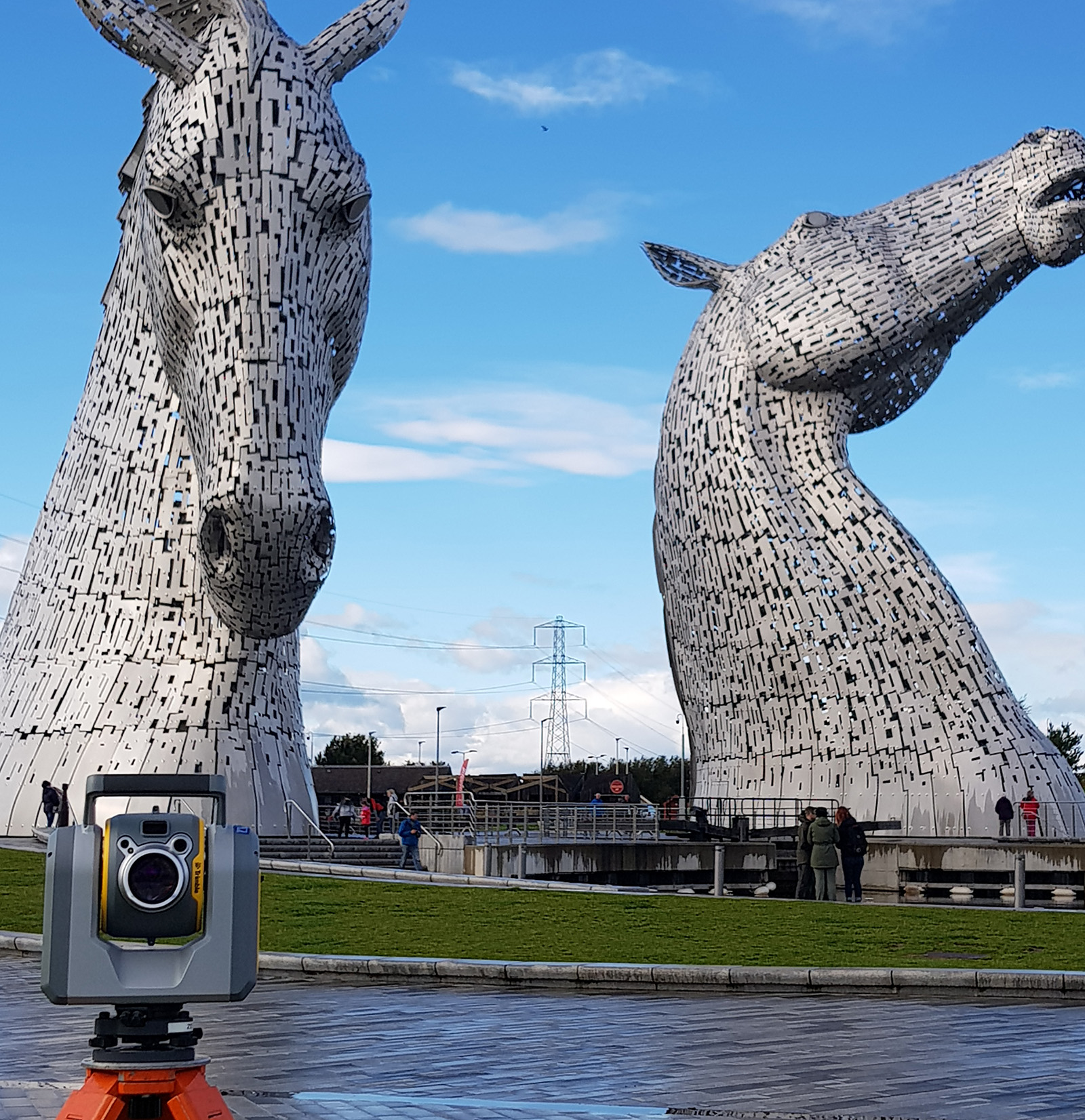 Surveying equipment in the foreground with Kelpies sculpture from Scotland in the background