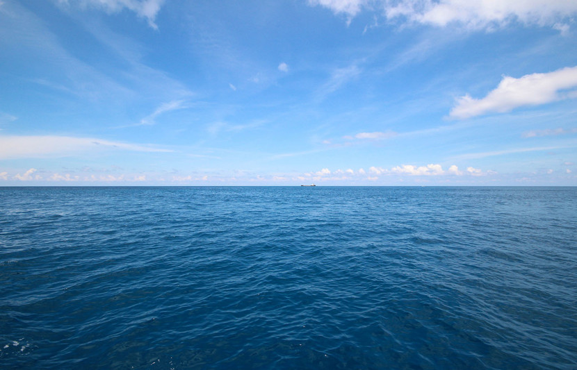 Blue ocean horizon with some clouds in the sky