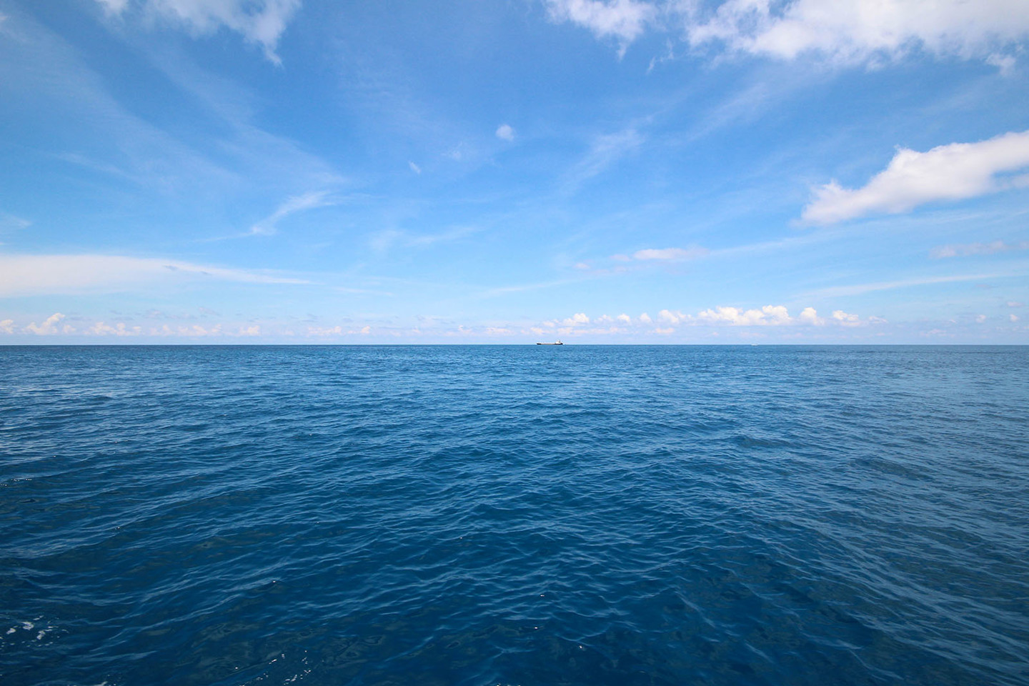 Blue ocean horizon with some clouds in the sky