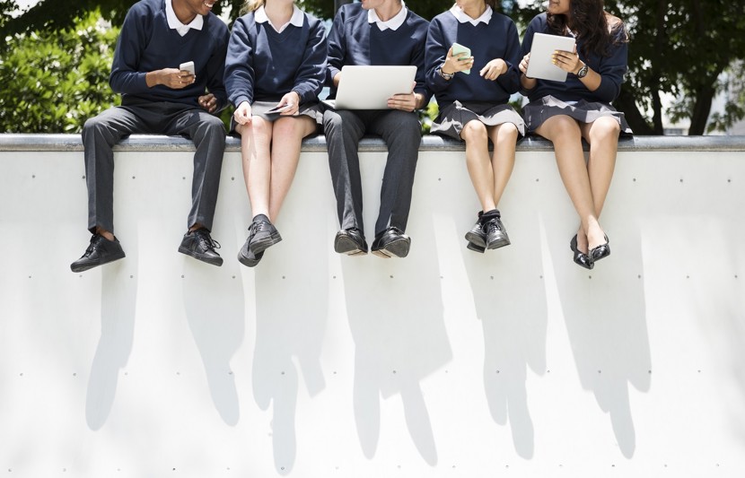 School children from an Advancing Clean Energy Schools Program school sitting on a bench outside working on a project together.