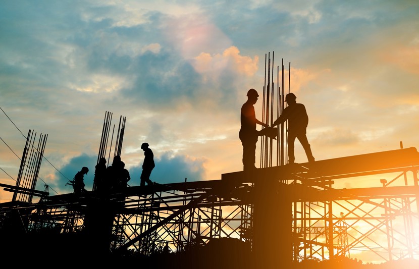 Construction workers on scaffold at sunset