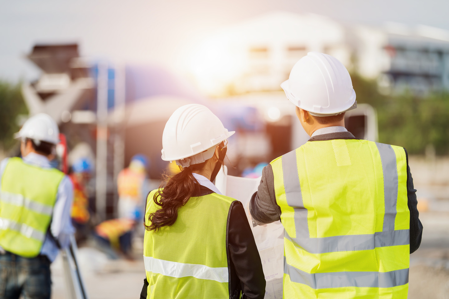 Two construction workers wearing hard hats look at a plan, one is female and one is male
