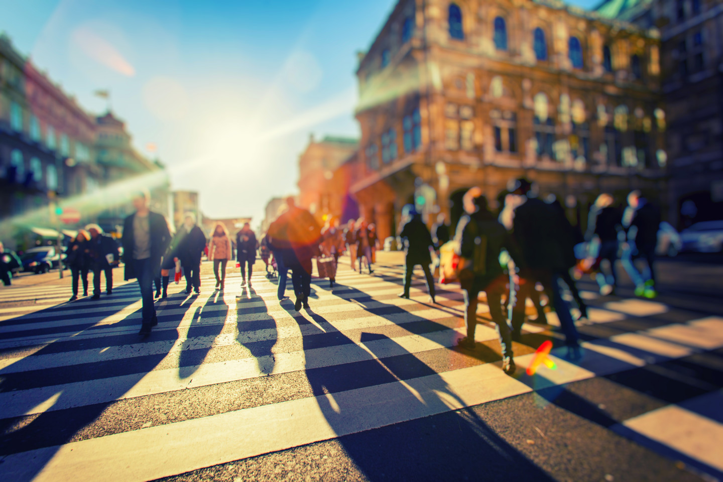 People walking sunny city street across pedestrian crossing
