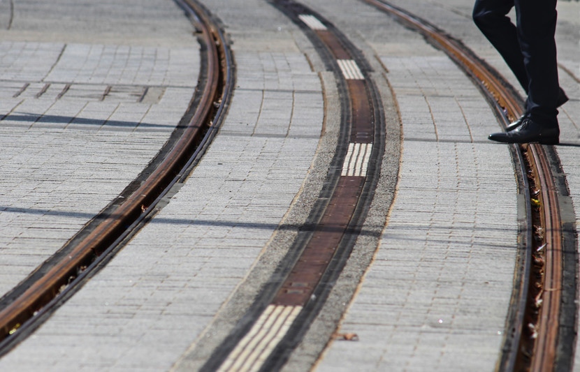 Pedestrian walking across empty tram tracks
