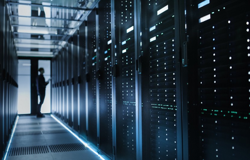 Man looking at data servers in a large server storage room