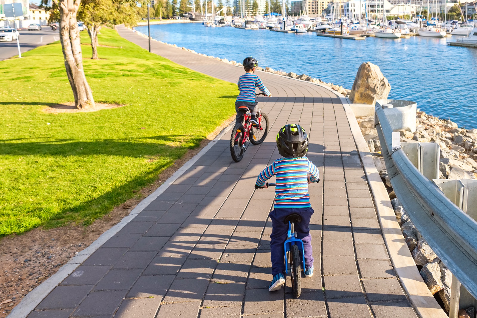 Kids riding their bikes along pathway near water