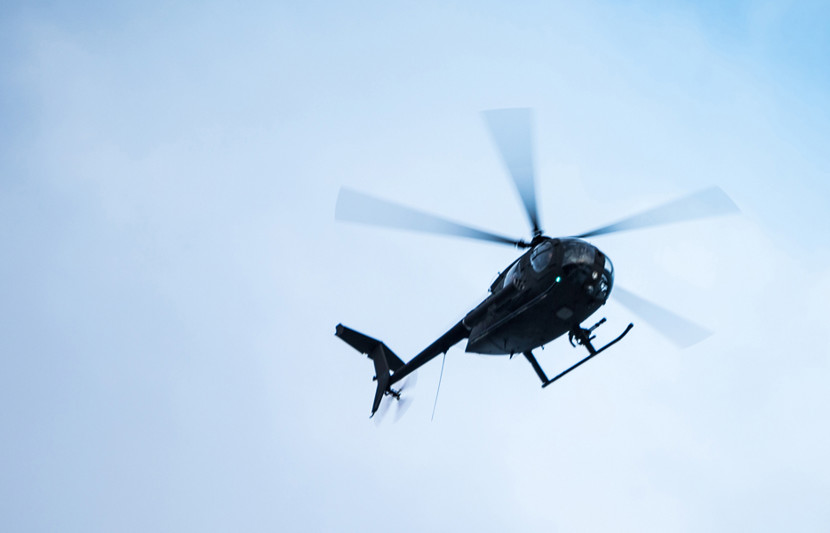 a helicopter flying against a cloudy sky