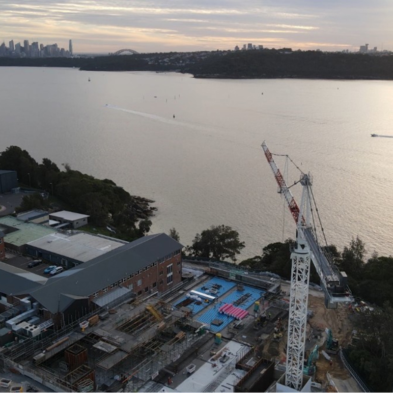 HMAS Watson at sunset with Sydney city skyline in background across Sydney Harbour