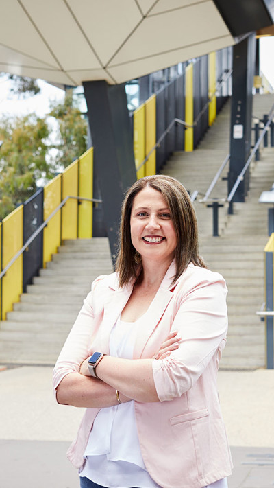 Mandi Davidson, RPS National Lead, Communications and Engagement stands outside and in front of yellow steps at the new Sunshine Train Station in Melbourne.