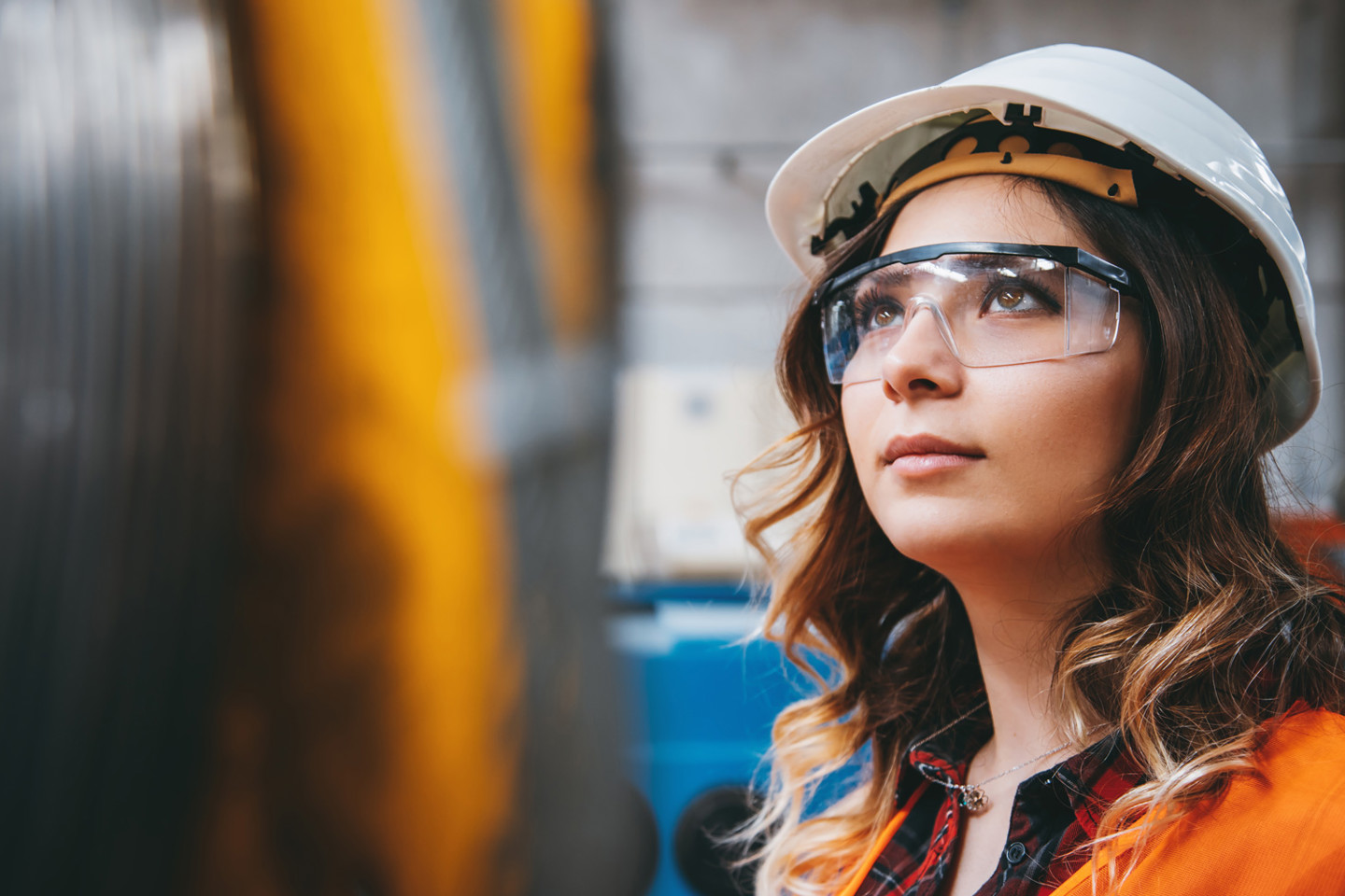 Woman in industry wearing hardhat and safety glasses