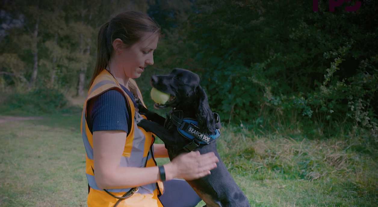 Female ecologist kneeling with detection dog