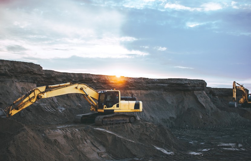 Mineral resource extraction site with yellow digger working on site