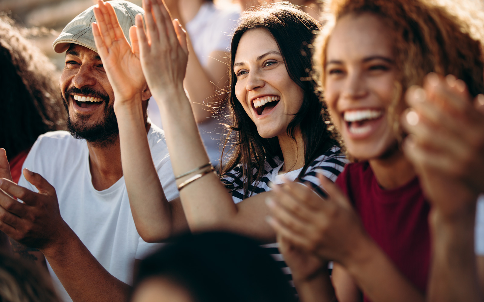 Group of young people smiling and clapping as if at a concert