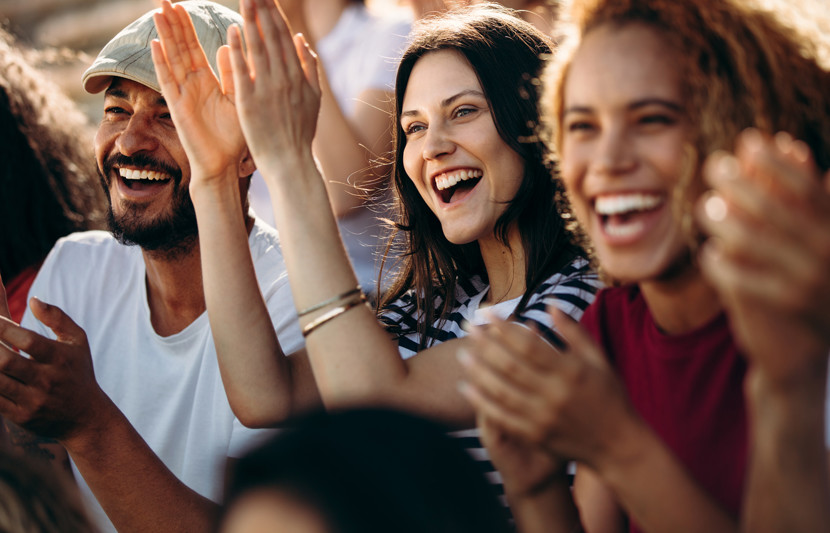 Group of young people smiling and clapping as if at a concert