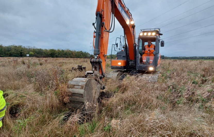 Digger surveying ground conditions on grass field