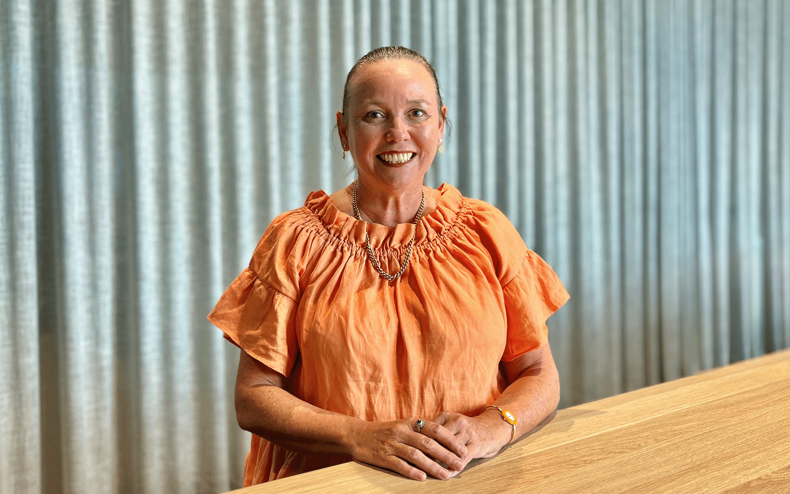 Jeanine Stone, RPS as Technical Director - Planning in Brisbane sits at table and smiles at the camera.