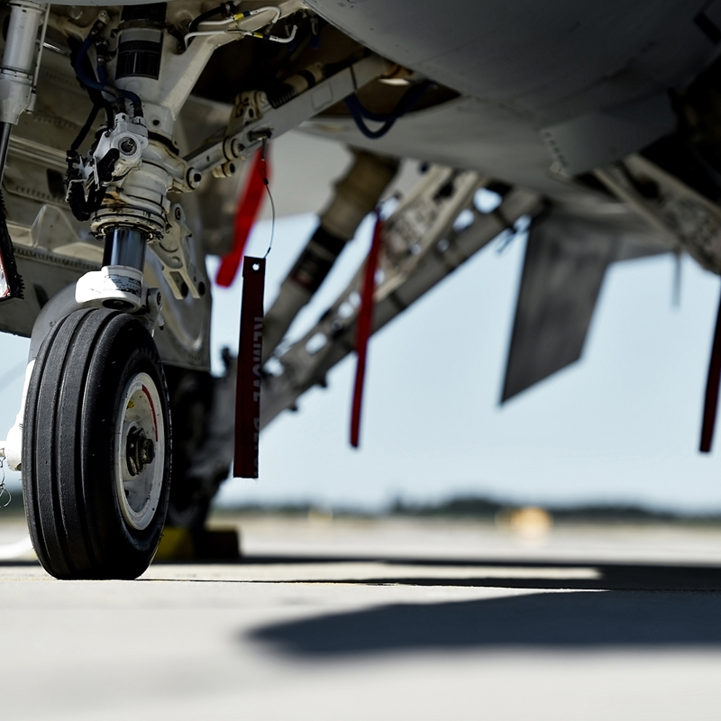 Defence sector expertise RPS 
Image: close up of jet landing gear and underside of fuselage of aircraft parked on an Air Force base.