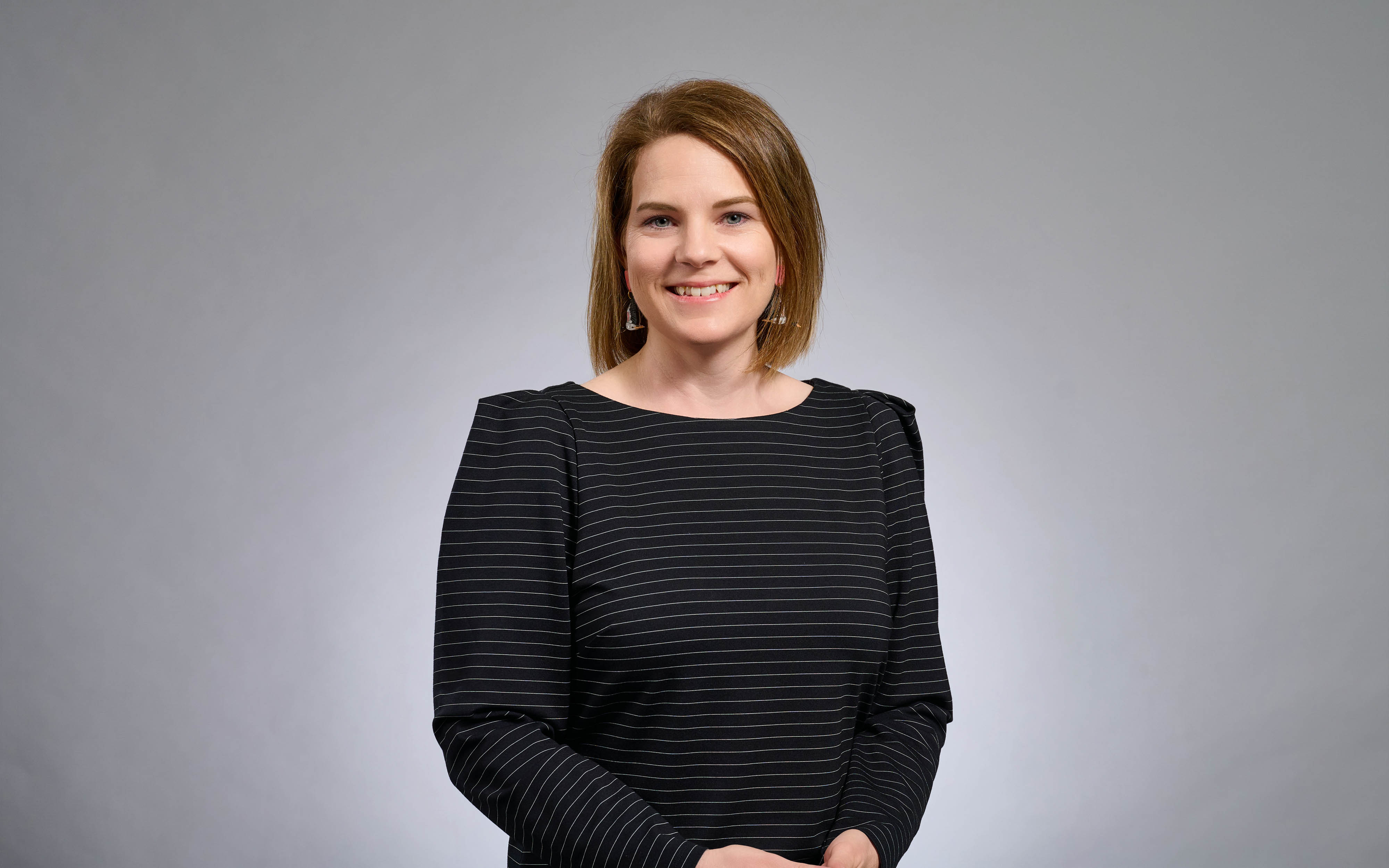 Claire Greenwell, RPS Senior Marine Scientist smiles at camera. Grey background to image